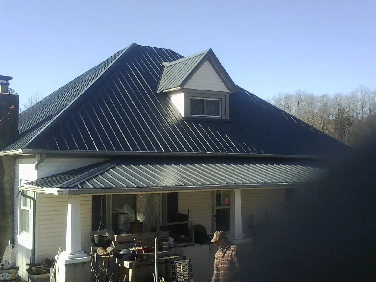 Dark blue standing seam metal roof with a dormer above a front porch in O Brien
